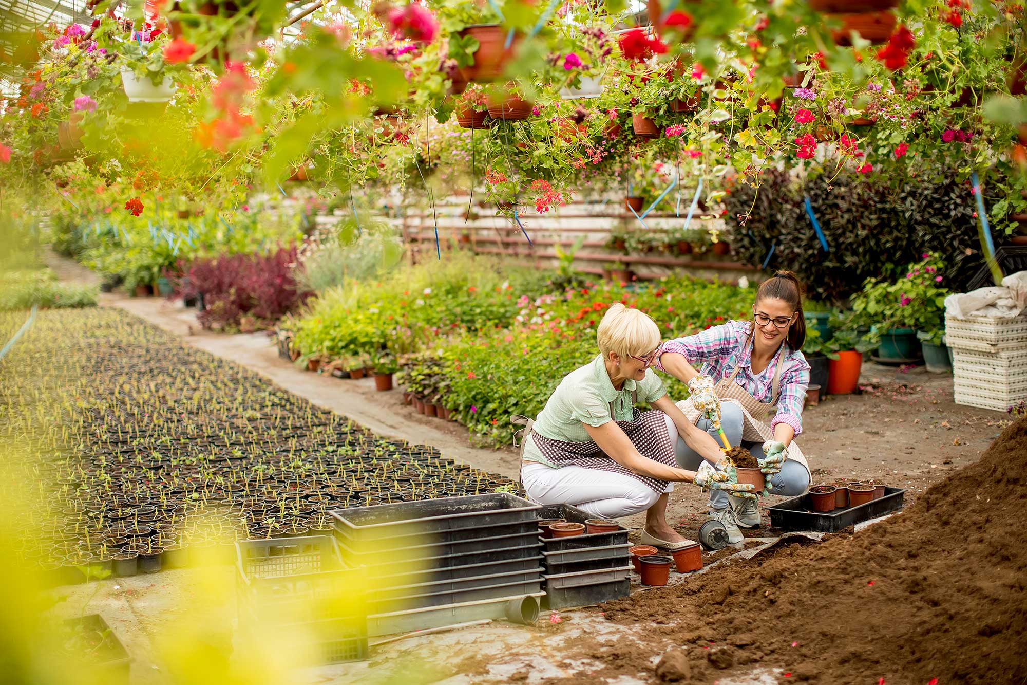 Mother and daughter filling pots with soil in the garden